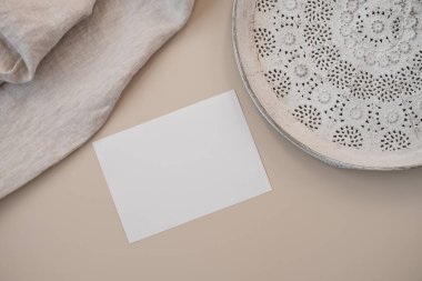 Fotokopi alanı, keten battaniye, tarafsız pastel bej arka planda zarif tepsi içeren boş kağıt davetiye kartları. Düz yatış, estetik minimalist düğün davetiyeleri