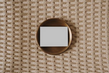 Fotokopi arkaplanında pirinç plaka olan boş bir kağıt kart. Üst görünüm, düz uzanan minimalist estetik lüks bohem ticari markalaşma kavramı