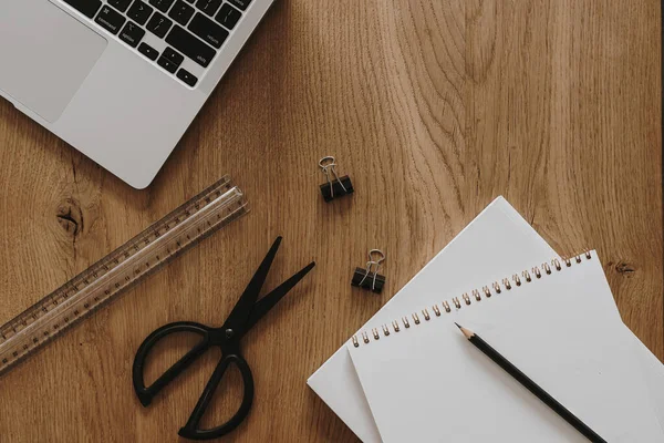 Laptop, defter, kahverengi ahşap masa zemininde kırtasiye malzemesi. Düzlük, üst görünüm estetik minimal serbest yazar, blog yazarı ofis çalışma alanı