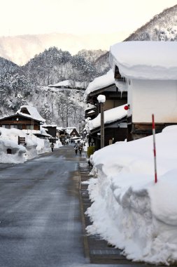 Shirakawago, Japonya - 24 Şubat 2022: Turistler kış mevsiminde Shirakawago köyünde karla kaplı bir sokakta geziniyorlar