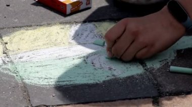 Küçük çocuklar renkli tebeşirle kaldırıma renkli resimler çizerler. Mutlu çocuklar renkli başyapıtlar çizerek yaratıcılığın tadını çıkarırlar.