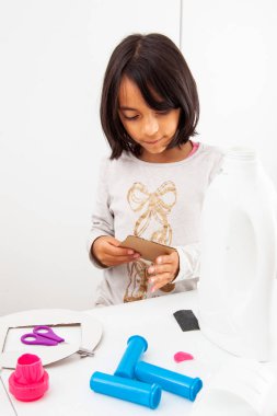Genç kız geri dönüşümlü malzemelerle oyuncak mikroskop yapıyor.