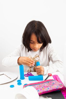 Genç kız geri dönüşümlü malzemelerle oyuncak mikroskop yapıyor.