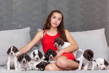 Küçük Fransız Braque köpeğiyle kırmızı giyinmiş güzel bir genç kız.