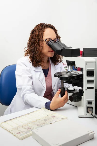 Cytologist looking at pap smear samples through a microscope. Medical analysis concept. Cervical cancer concept.