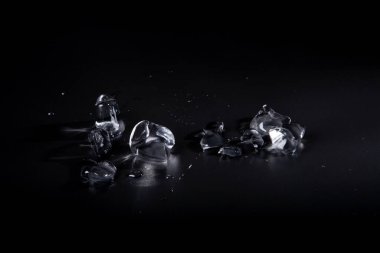 Siyah zemin üzerinde şeffaf buz parçaları. Arka planda su birikintilerindeki buz kütleleri. Yukarıdan buz görüntüsü.