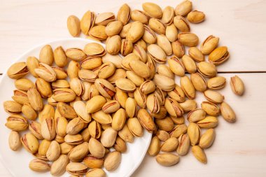 Beyaz tahtaların arka planında tuz olan kabuklu fıstık. Bira aperatifi - tuzlu fındık. konsept abur cubur