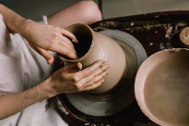Beyaz gömlekli genç kız çömlekçi çarkında bir sürahi kil yapıyor. Yaratıcı bir kadının çömlek atölyesi. Kavram - hobi kil