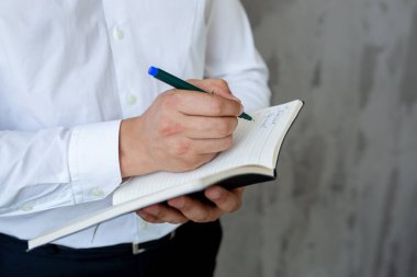 Kot pantolon ve beyaz gömlekli erkek danışman elinde açık siyah bir defter tutuyor. finansal planlama. Kavram - iş dünyasındaki geleneksel teknolojiler