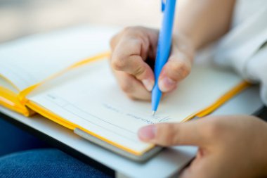 Kot pantolonlu ve beyaz bluzlu danışman kız elinde açık sarı bir defter tutuyor. finansal planlama. Kavram - iş dünyasındaki geleneksel teknolojiler