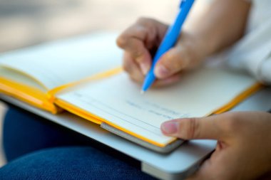 Kot pantolonlu ve beyaz bluzlu danışman kız elinde açık sarı bir defter tutuyor. finansal planlama. Kavram - iş dünyasındaki geleneksel teknolojiler