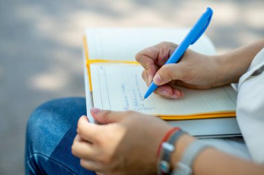 Kot pantolonlu ve beyaz bluzlu danışman kız elinde açık sarı bir defter tutuyor. finansal planlama. Kavram - iş dünyasındaki geleneksel teknolojiler