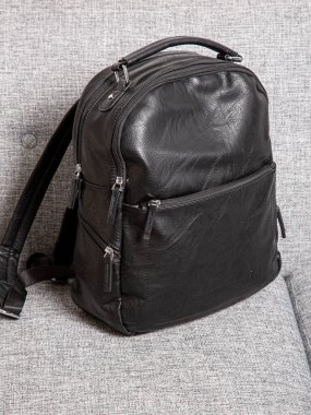 Fermuarlı kayışlı siyah sırt çantası. Eşyalar, aksesuarlar ve ders kitapları dairenin içinde..