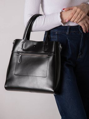 Sırtında kayışlar olan siyah bir sırt çantası. Eşyalar, aksesuarlar ve ders kitapları için bir çanta. Kilitli deri sırt çantası..