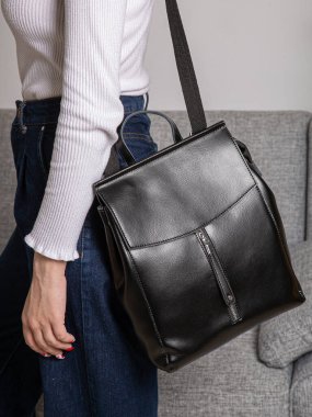 Sırtında kayışlar olan siyah bir sırt çantası. Eşyalar, aksesuarlar ve ders kitapları için bir çanta. Kilitli deri sırt çantası..