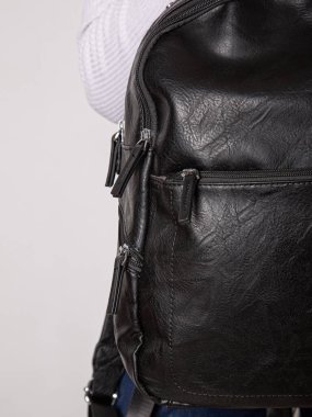 Fermuarlı kayışlı siyah sırt çantası. Eşyalar, aksesuarlar ve ders kitapları dairenin içinde..
