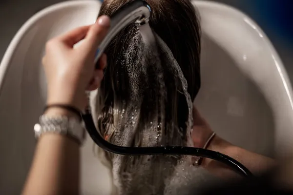 理发师用洗发水和护发素在一个白色洗发池中洗头 概念是女孩的美容院 — 图库照片