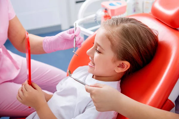 Küçük kız dişlerini pediatrik bir dişçiye göstermekten korkuyor. Çocuk doktorunun resepsiyonundaki beyaz elbiseli kız gülümsedi ve güldü. konsept çocuk sağlığı..