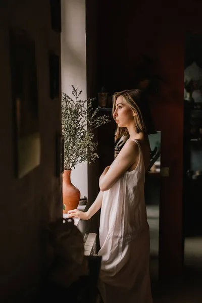 身穿轻便睡衣的天才雕塑家女孩站在靠近大窗户的陶瓷作坊里 概念就是美 免版税图库图片