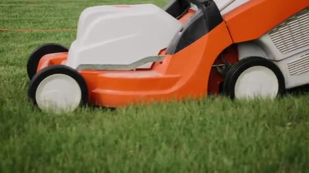Close-up tracking shot van een maaien van het gras in de achtertuin met een elektrische grasmaaier. Langzame beweging — Stockvideo