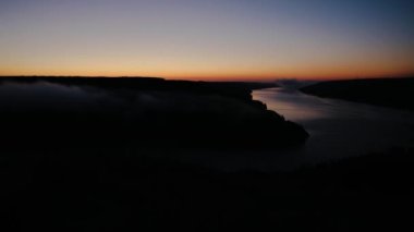 Timelapse of misty sunrise over Dniester river canyon. Fog rising over water and hills in the morning. Thick white clouds on the beautiful landscape background. Dnister river in Ukraine