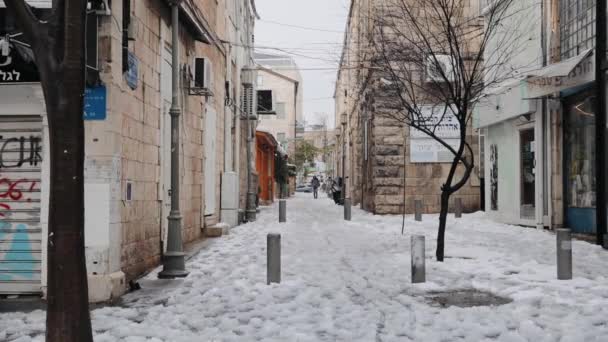 Χιόνι σε μια άδεια πόλη. Βαριά χιονόπτωση στην πόλη της Ιερουσαλήμ. Δύσκολο να περπατήσεις σε χιονισμένο πεζόδρομο. Ιερουσαλήμ, Ισραήλ, Ιανουάριος 2022 — Αρχείο Βίντεο