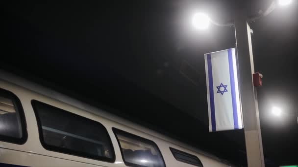 Bandera de Israel en la noche cerca del tren. Estación principal de tren en la capital de Israel - Jerusalén — Vídeos de Stock