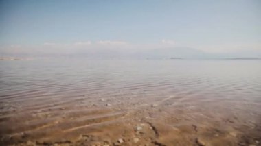 Güneşli bir günde uzak deniz ve sahil manzarası. İsrail, Ein Bokek yakınlarında ölü bir deniz. Sakin bir havada Ölü Deniz kıyısında