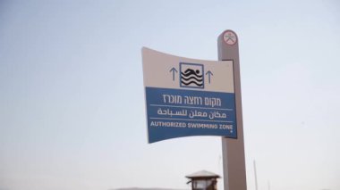 Plajdaki resmi yüzme sahası hakkında bilgilerle imzalayın. İbranice ve Arapça 'da yüzmeye izin verildiği anlamına gelir.