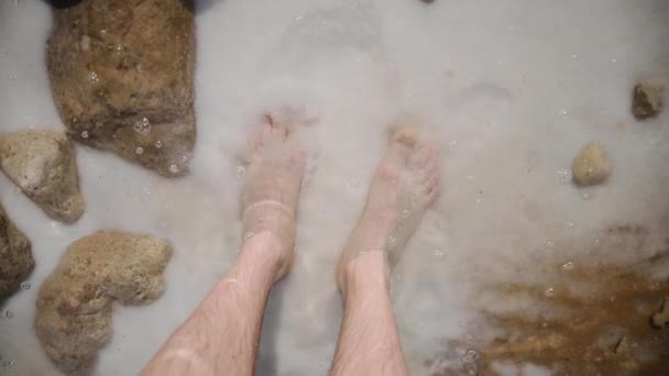 Зверху ви бачите людські ноги, які миються морською водою з сіллю. Берег Мертвого моря (Ізраїль). — стокове відео
