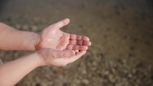 Vista de cerca de las manos del hombre sobre el fondo de agua de mar. En la playa del Mar Muerto. Agua muy salada que dejó efecto maravilla en la piel humana — Vídeos de Stock
