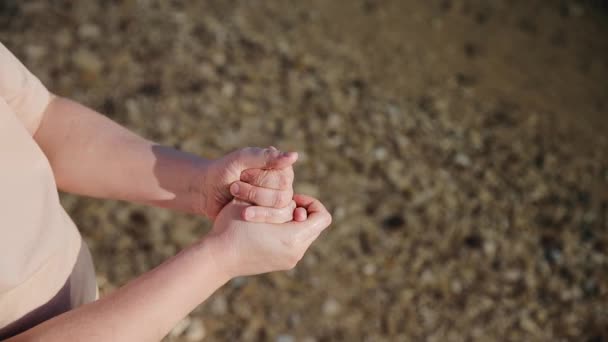 O homem esfrega as mãos com água do mar. Na praia do Mar Morto. A água de sal evaporada deixa um efeito de brilho em mãos de homem — Vídeo de Stock