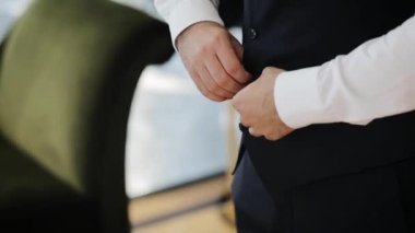 Stylish arabic young man in a suit buttoning black jacket. Close up of groom preparing at the morning for engagement