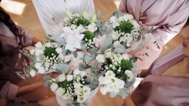 Close up view of faceless bridesmaids holding wedding bouquet with white roses and other different flowers. Bride and bridesmaids posing with bouquets. Wedding decoration ideas