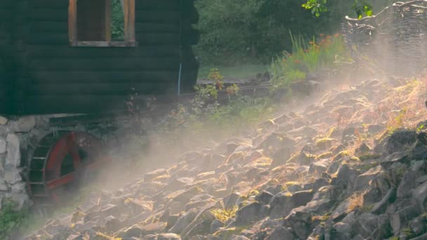 Pietre riscaldate al sole evaporare dopo la pioggia. Una leggera nebbia sulle rocce. Ruota in legno ruotante dal flusso dell'acqua. — Video Stock