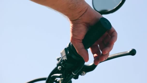 Primer plano de una manopla de mano en el manillar de una motocicleta. Motociclista aprieta el gatillo del gas sobre un fondo de cielo azul. — Vídeo de stock