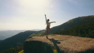 Dağların arkasında bir kayanın üzerinde dans eden kız. Doğaçlama dansçı kız dağlarda turist.