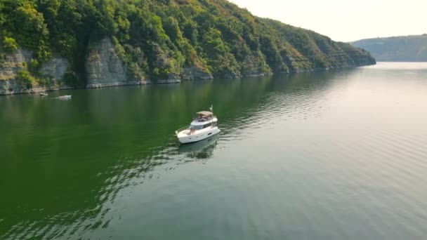 Luchtfoto Eenzame boot bij de rotsachtige kust. Vlucht rond een boot die vlak bij de kust staat. Een toeristisch boot staat nabij een rots in een zee baai. — Stockvideo