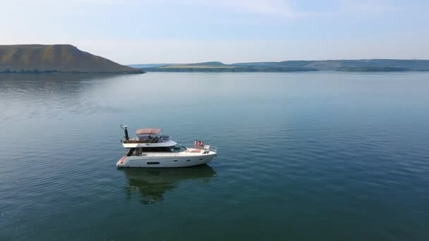 Letecké Shot Luxusní jachty v blízkosti skalnatého pobřeží. Letí kolem lodi stojící u břehu. Turistický člun stojí u skály v zátoce. — Stock video