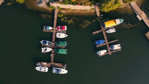 Aerial top view from the top on a small pier of motor boats located on the river. Tourist and fishing boats at sunrise view from above. — Stock Video