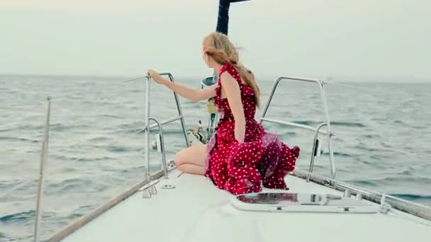 Дівчина в вечірній сукні стоїть на яхті на заході сонця. Вечірня подорож на човні. Жінка в елегантній сукні, що піднімає вітер. Щаслива жінка на яхті в чистому морі — стокове відео
