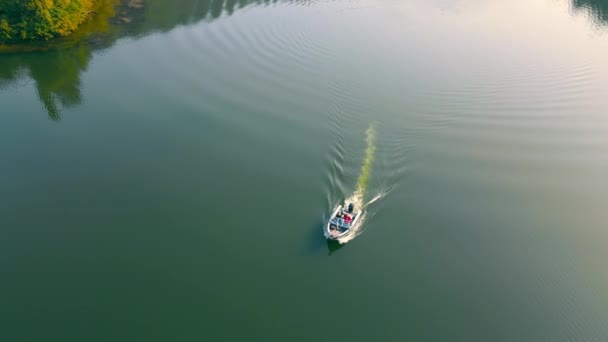 Вид с воздуха Моторная лодка, плывущая по реке с двумя людьми. Солнечные лучи отражаются в воде. Прогулка на моторной лодке. Скоростной катер. — стоковое видео