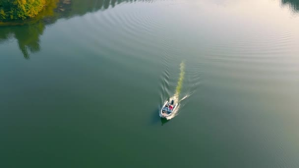 Vista aérea Barco a motor navegando por el río con dos personas. Los rayos del sol se reflejan en el agua. Un paseo en un barco a motor. Velocidad de pesca. — Vídeo de stock