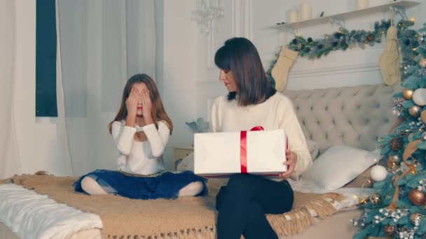 Madre le da al niño una caja grande con un regalo de Navidad. Felices emociones del niño que recibió el regalo. Esterilla y niña feliz juntos. — Vídeos de Stock