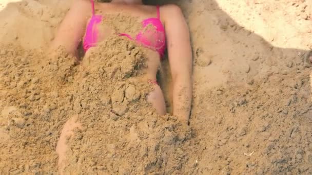La mujer está enterrada en la arena con una pala. Mucha arena en el cuerpo de una mujer. — Vídeos de Stock