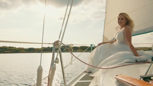 Brud på en yacht vid solnedgången. Bruden blickar i fjärran, solen strålar — Stockvideo