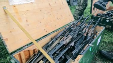 Ordu Kalaşnikof saldırı tüfekleri ve keskin nişancı tüfeklerini bir kutuya koydu. Askeri teçhizat boşaltılıyor. Yakın çekim bir kutu makinesine koyar.