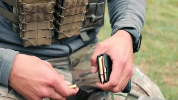 Han tömmer butiken med ammunition. En militär soldat drar kulor ur hornet på en kulspruta. — Stockvideo