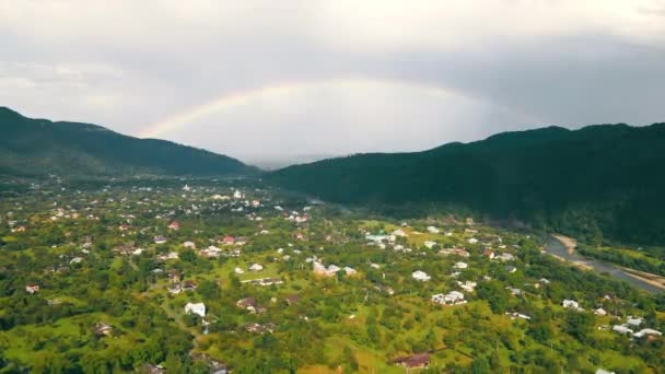 Survolez le village dans les montagnes après la pluie. Arc-en-ciel après la pluie à l'horizon. — Video