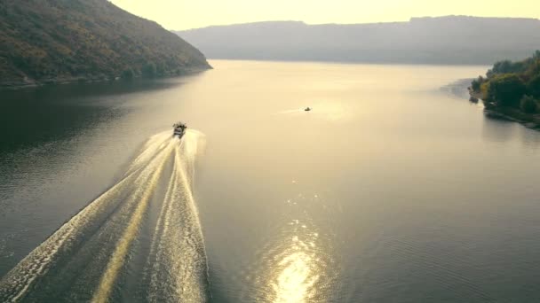 Vuelo sobre una lancha que se mueve en el lecho del río. Las olas divergen del movimiento del barco en el río. Entrega rápida de mercancías en el río. — Vídeo de stock